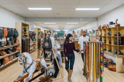 couple looking at leather goods, belts, hats and bags at Awl Leather